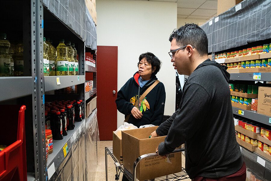 a man helps a woman shop at a food pantry