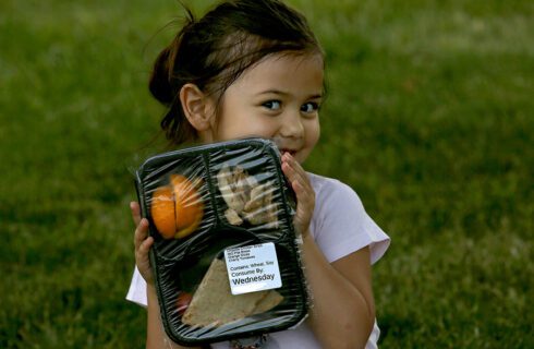 a young girl holds a packaged lunch