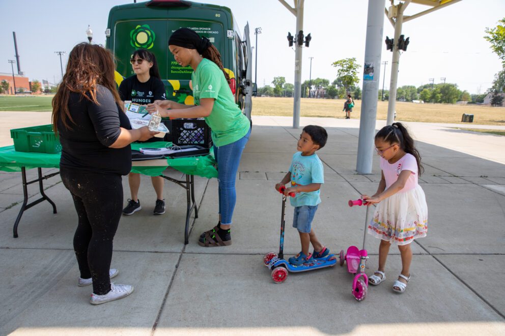 two kids and their mom at a lunch bus site