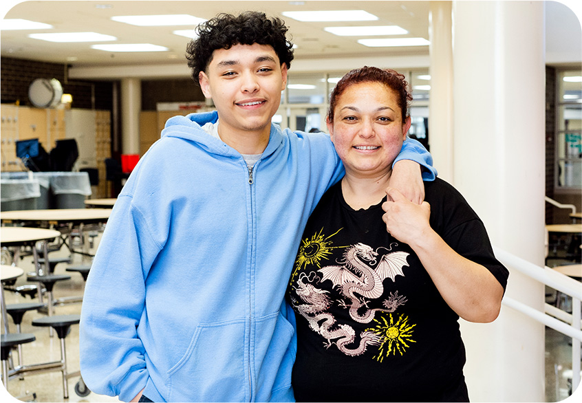 A mom and son smiling together after the young man received a meal from the youth program.