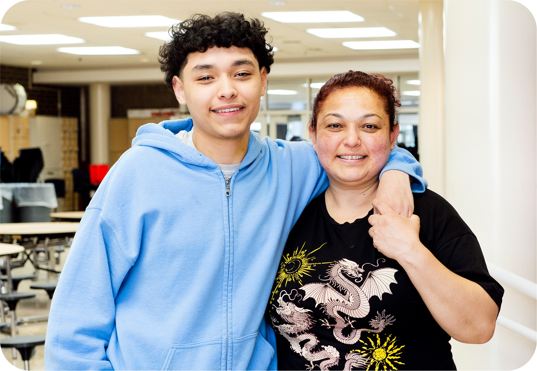 A mom and son smiling together after the young man received a meal from the youth program.