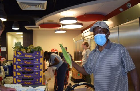 a man holds up an ear of sweet corn at a food pantry