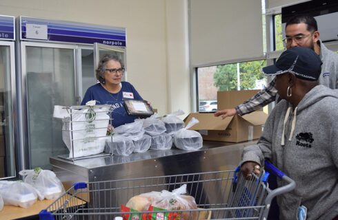 a volunteer offers a prepared meal to a pantry guest