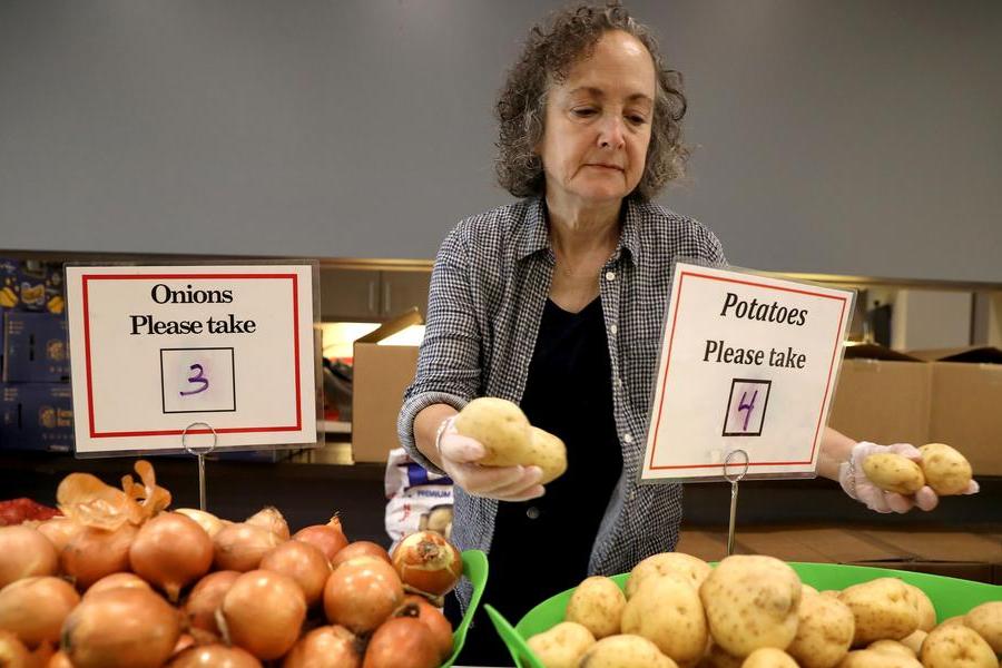 Volunteer distributes onions and potatoes at a food pantry.