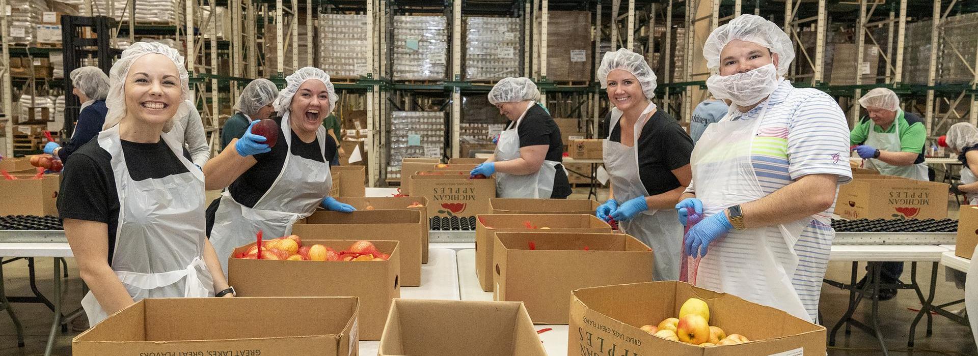 A group of food pantry volunteers packing apples