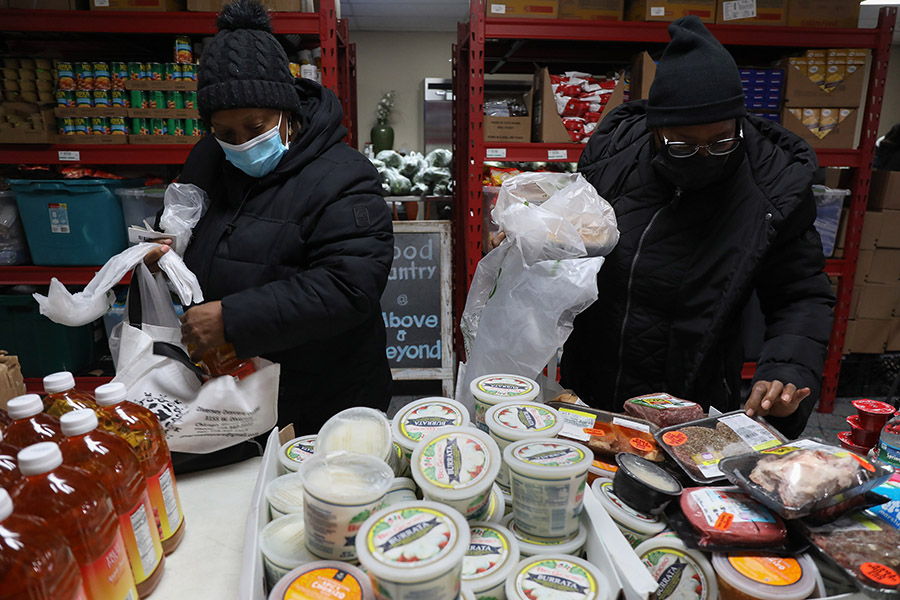 Two women select items at a food pantry