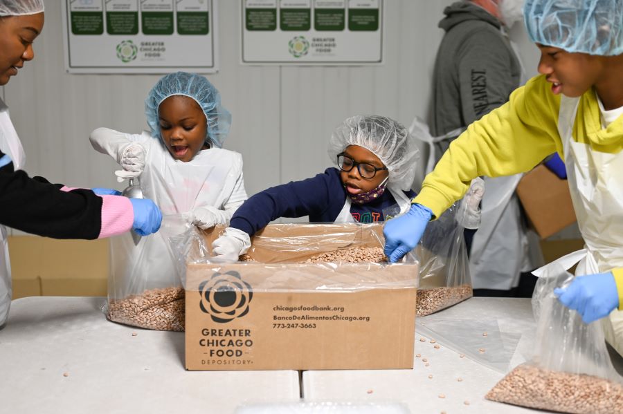 A woman and three children scoop dry beans into individual bags.