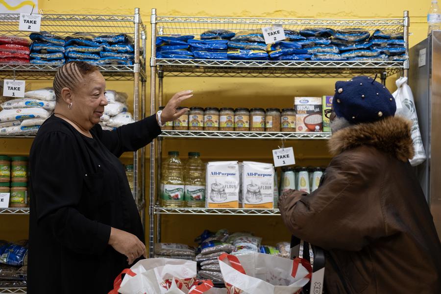 A Seeds Center volunteer helps a pantry guest pick out food.