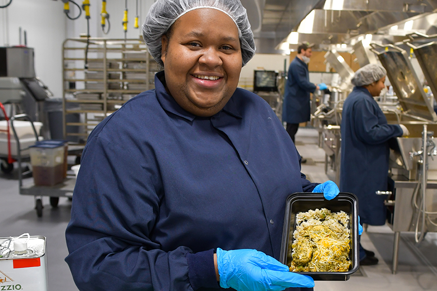 a cook holds up a prepared meal in a kitchen