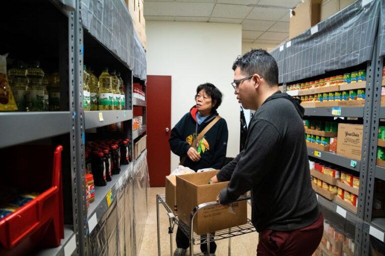 Man helping woman at pantry pick food.