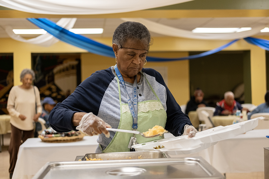 a woman dishes food onto a paper plate