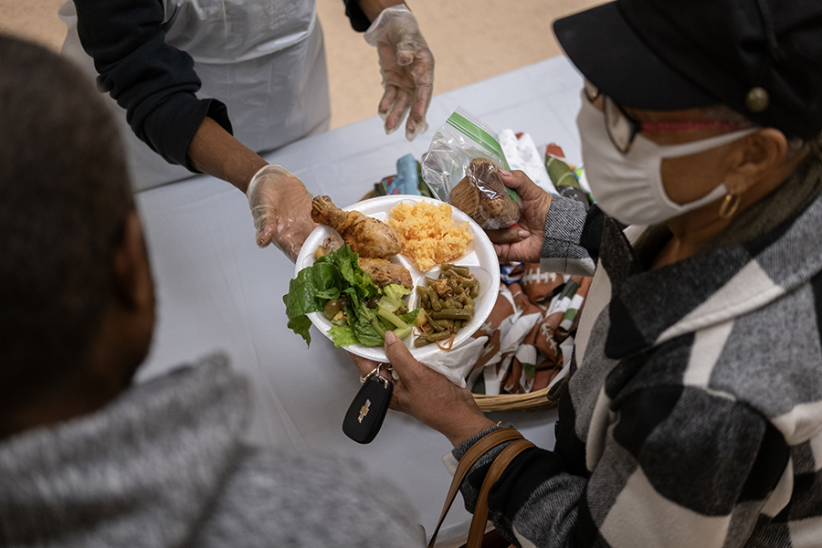 someone hands a woman a plate full of food