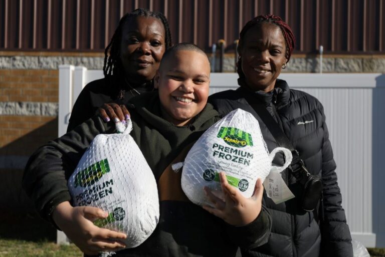 Two adults and child receiving frozen turkeys.