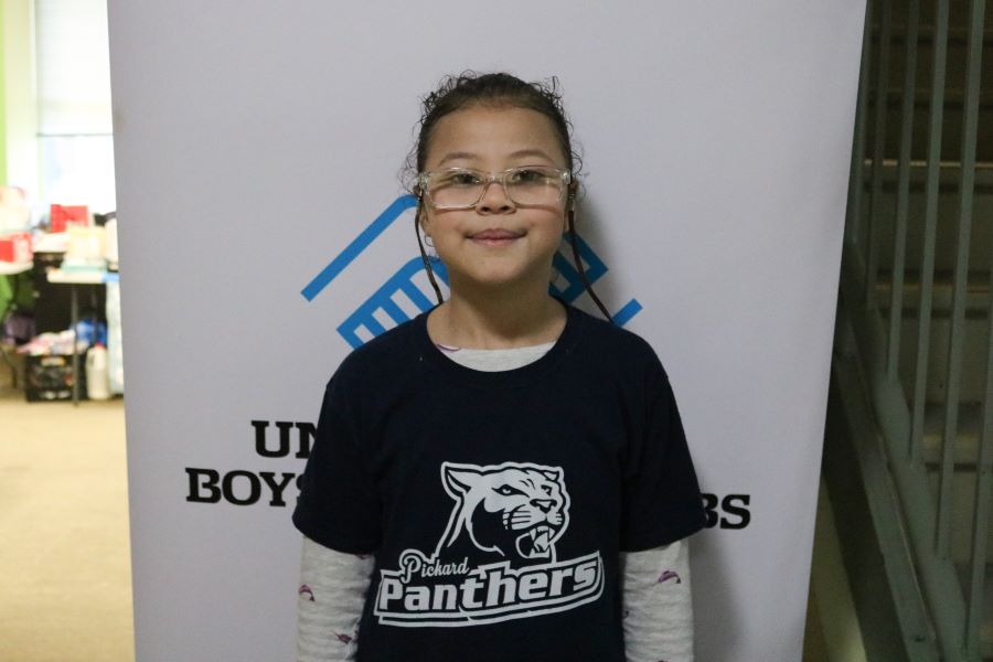 A girl in glasses stands in front of a door.