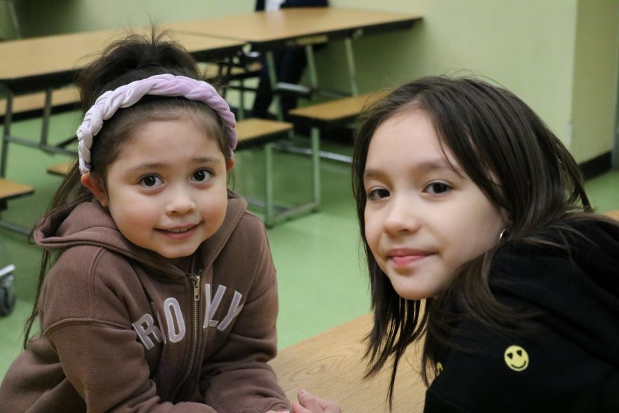 Two girls sit together at a table.