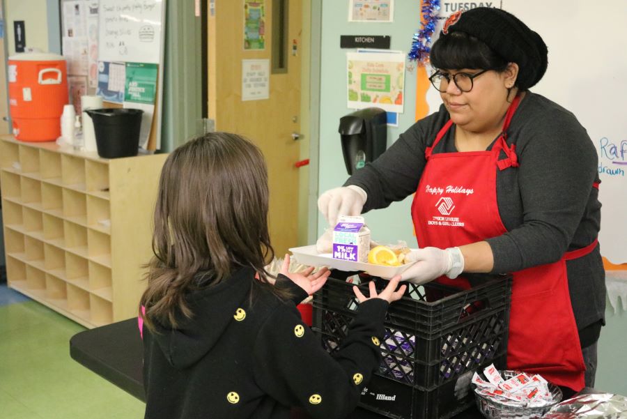 A woman serves a girl food.