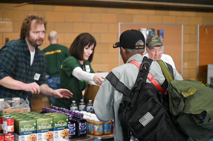 A man and woman give food to another man.