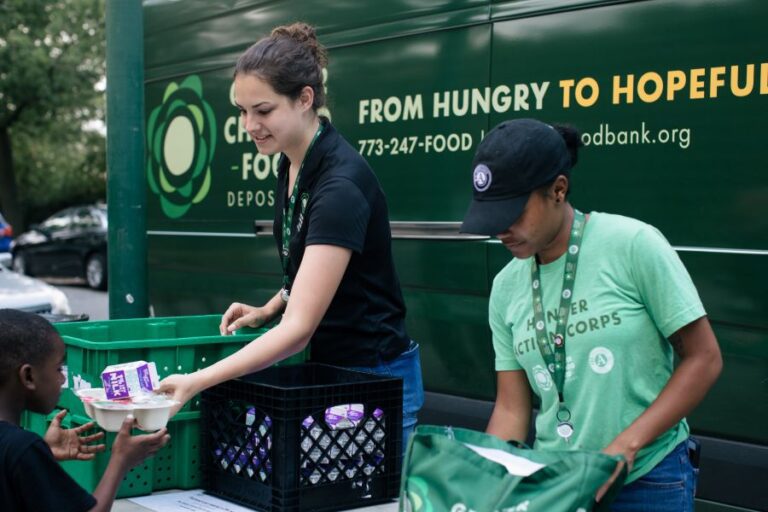 Two people handing out summer lunches.