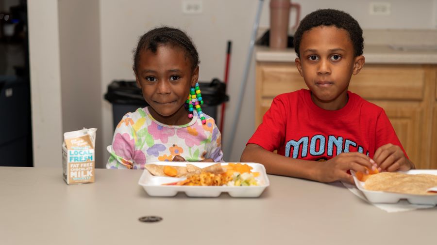 Two children sit together with food.