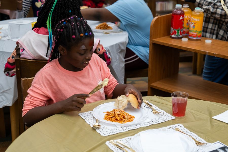 A girl sits at a table to eat a meal.
