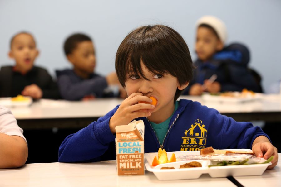 A boy bites into an orange.