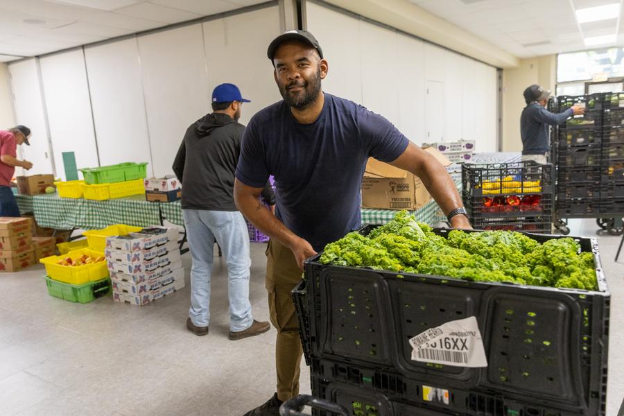 A man pulls a cart of produce.