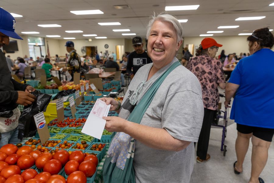 A woman smiles at the camera holding a coupon.