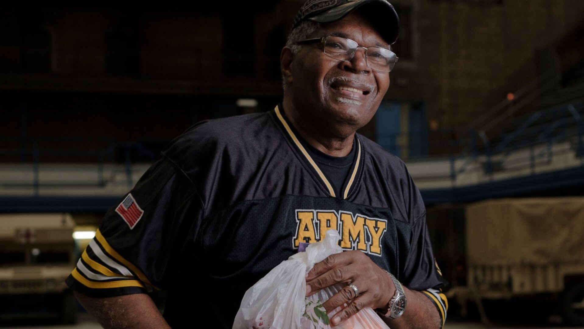 Man in an Army t-shirt holds a shopping bag