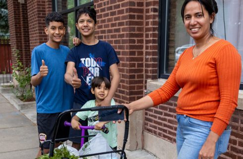 a woman and three boys stand with their groceries in front of a food pantry