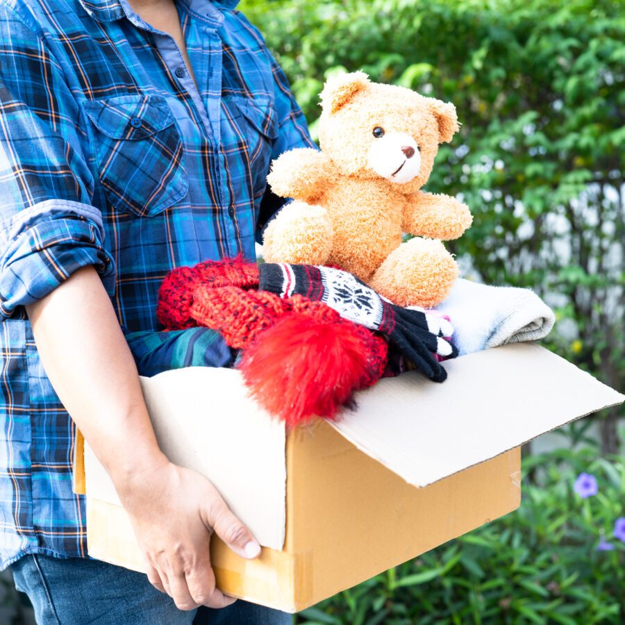 holding-clothing-donation-box-with-used-clothes-and-doll-at-home