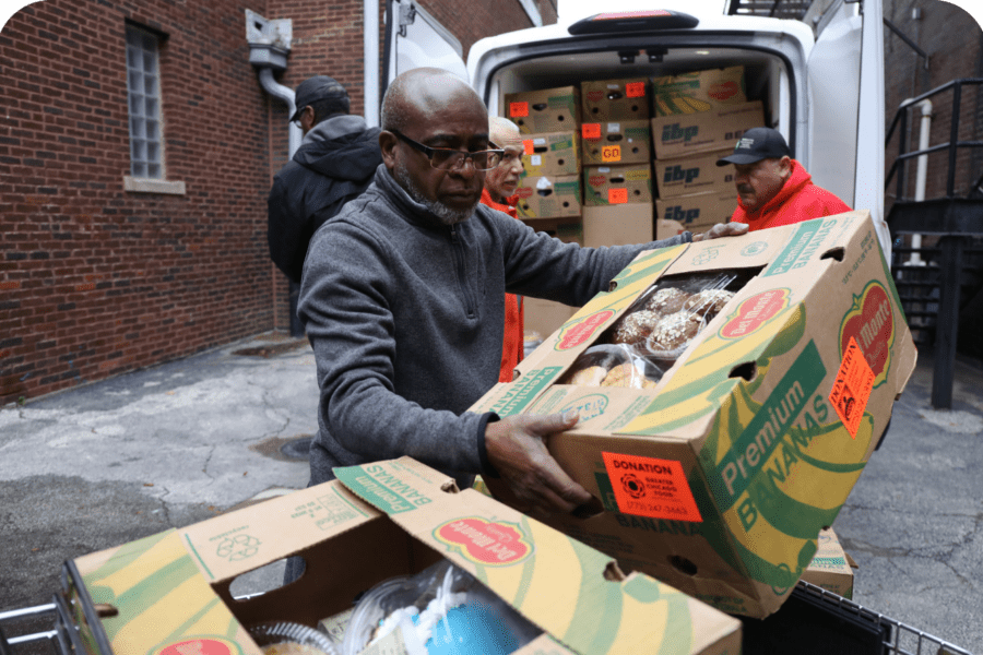 Male volunteer helps load cases of food onto a distribution truck.