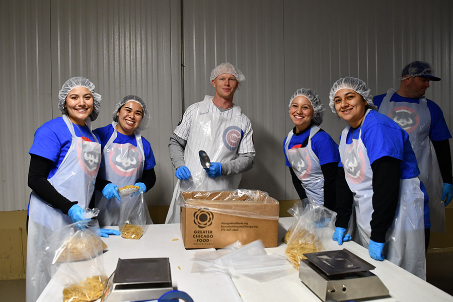 volunteers and a Cubs player smile at the camera