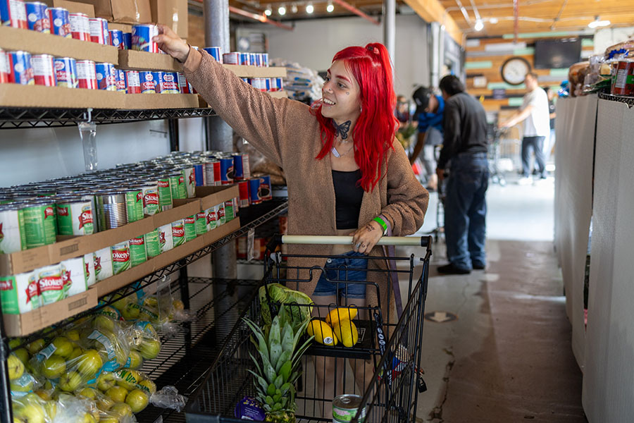 a young woman with red hair shops for food at a pantry