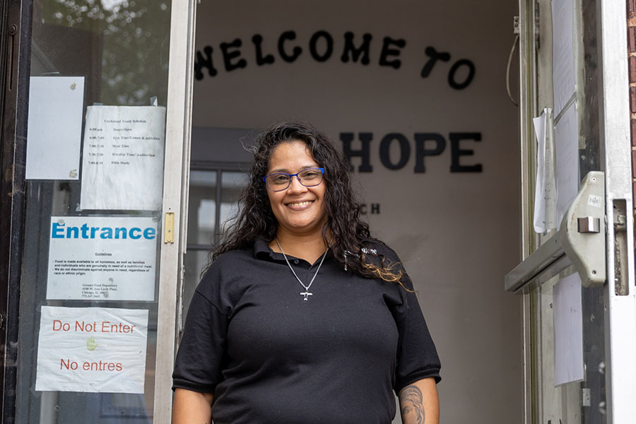 A woman stands in the doorway of a food pantry smiling at the camera