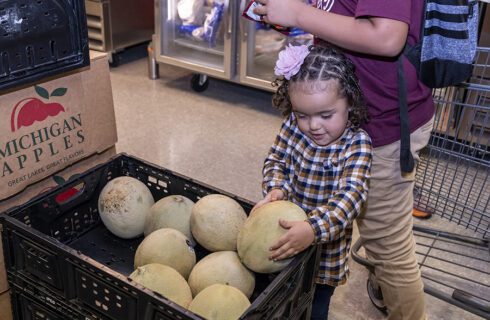 A young girl chooses a melon at a food pantry