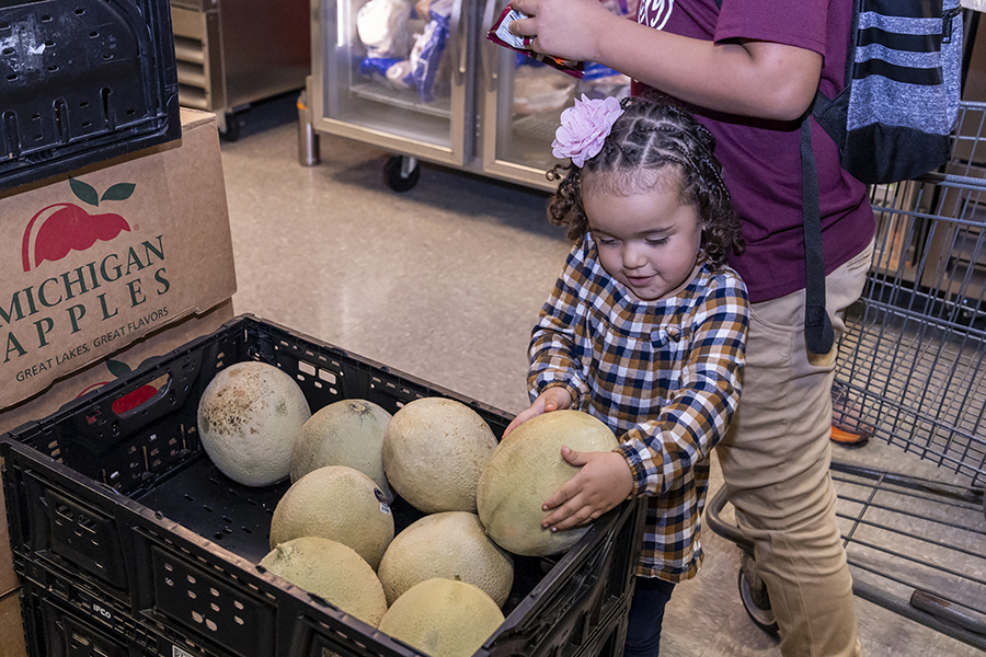 A young girl chooses a melon at a food pantry