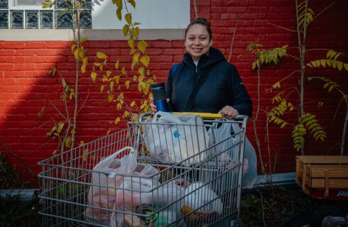a woman stands with a shopping cart full of food