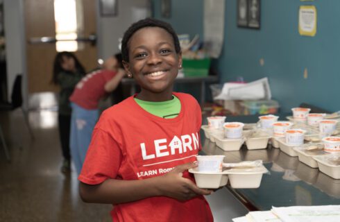 a young boy holding a snack smiles at the camera