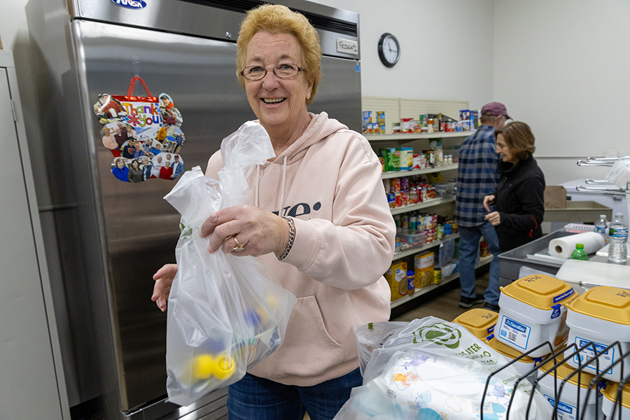 A volunteer is holding a grocery bag and smiling
