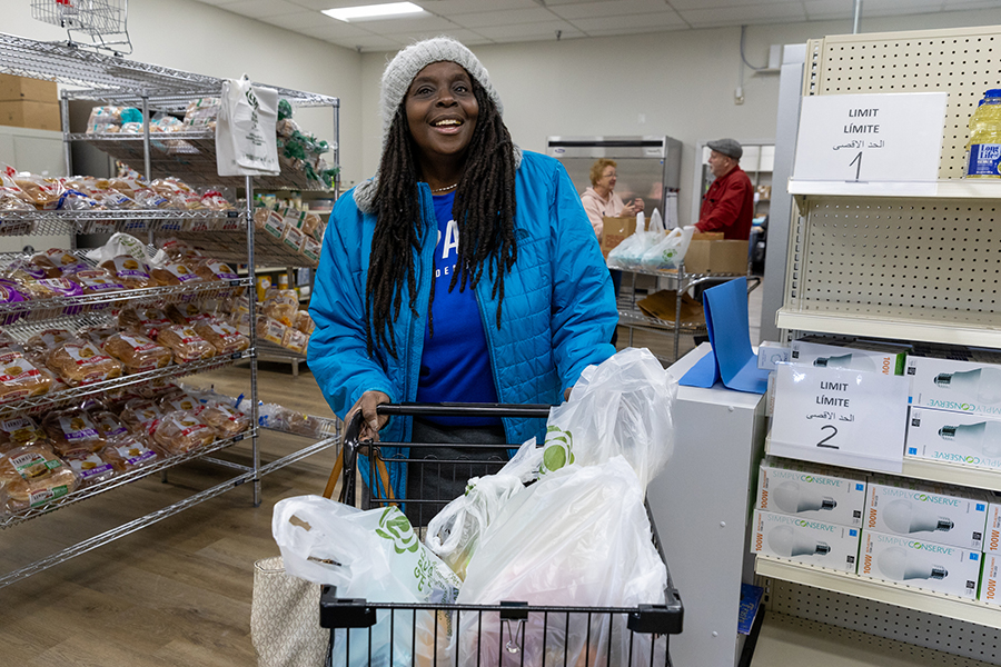 A woman at a food pantry smiles at the camera