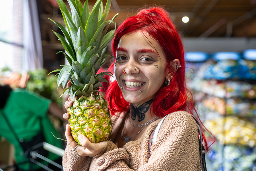 a food pantry guest holds a pineapple and smiles at the camera