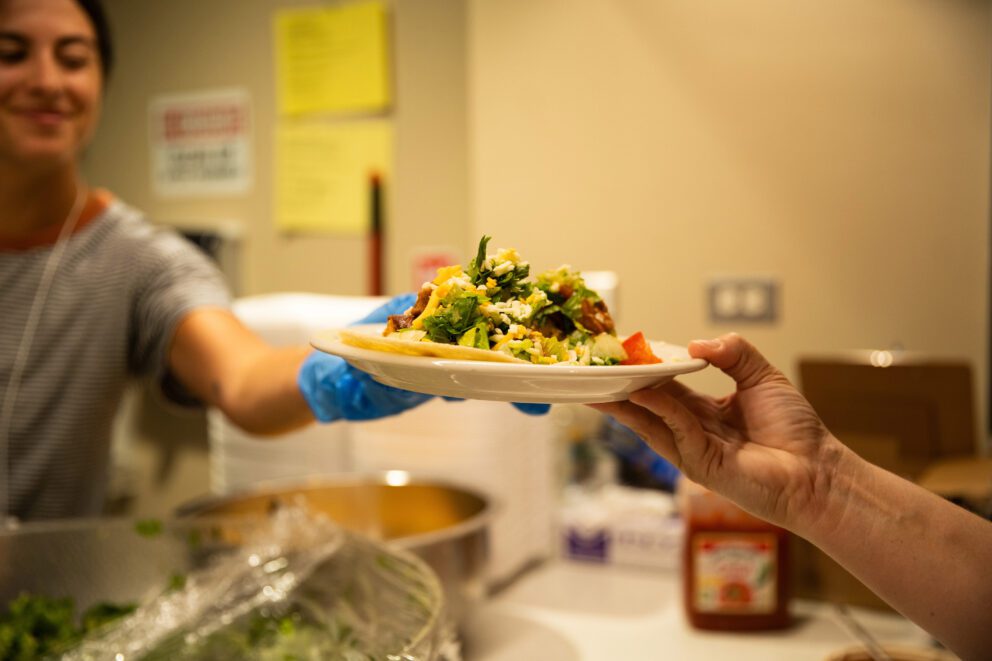 a volunteer hands a plate of food to a guest