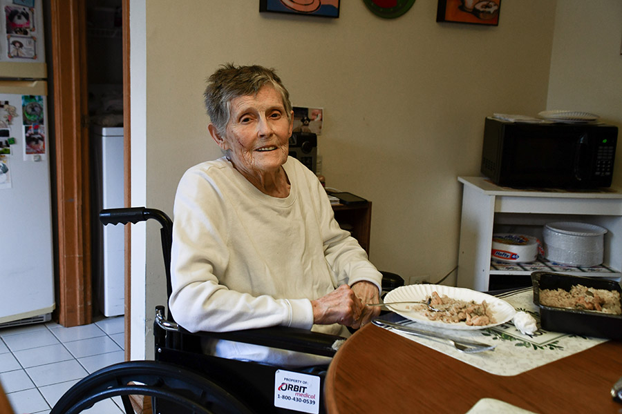 an older adult sits at a table about to eat a meal