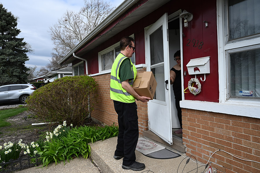 A driver delivers a box of meals to a woman's front door