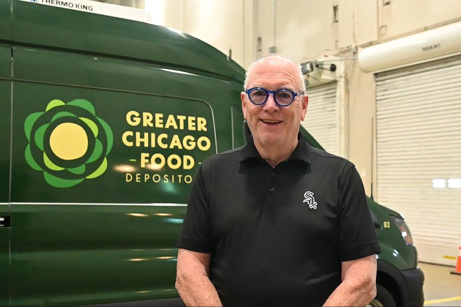 a man stands smiling next to a Food Depository delivery van