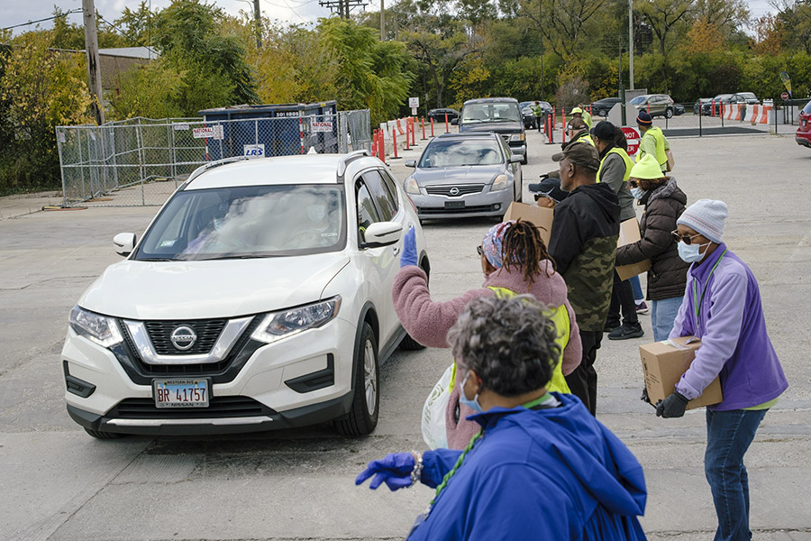 Volunteers wait for a new line of cars to receive food boxes